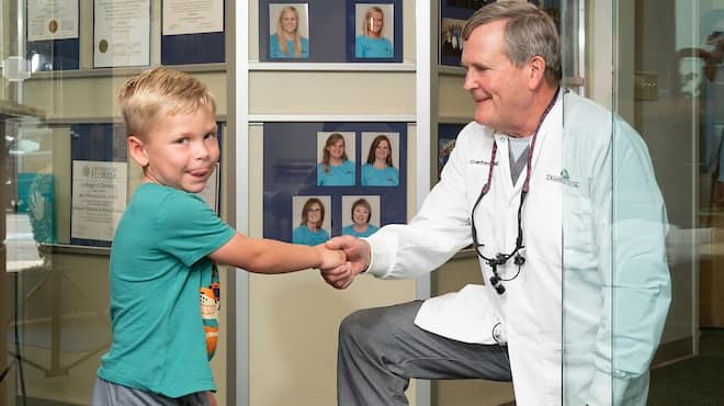 Dentist Bill Cranford shaking hands small boy