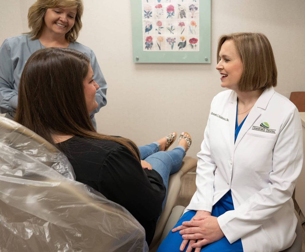 Dr Elizabeth Robinson consulting with a patient while hygienist looks on