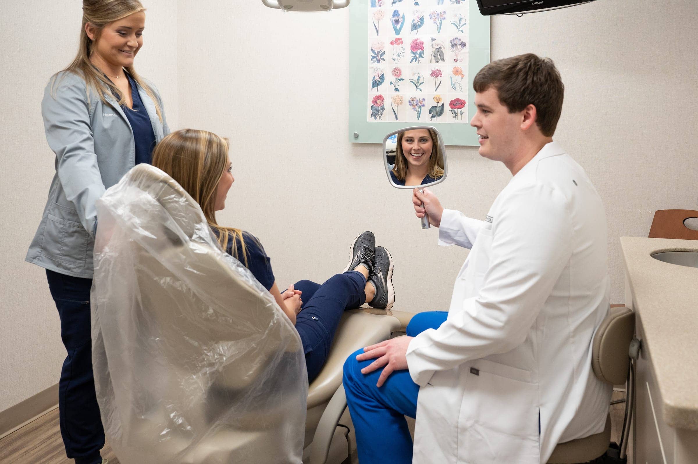 Dr Will Robinson showing patient her white teeth in a mirror while assistant looks on
