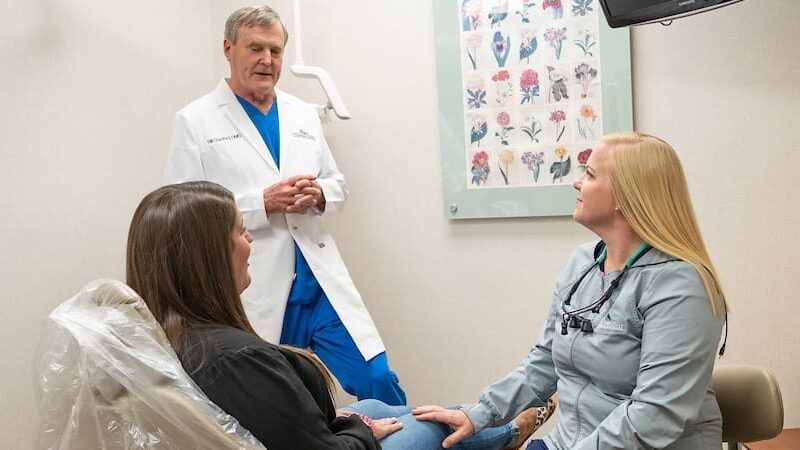 Dentist standing at chair giving crown home instructions to patient